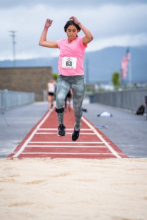 Athlete in pink leaps into the long jump pit at the 2022 Pine Cone Classic