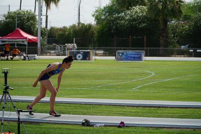 Athlete in a blue top leans into the start of a runway approach