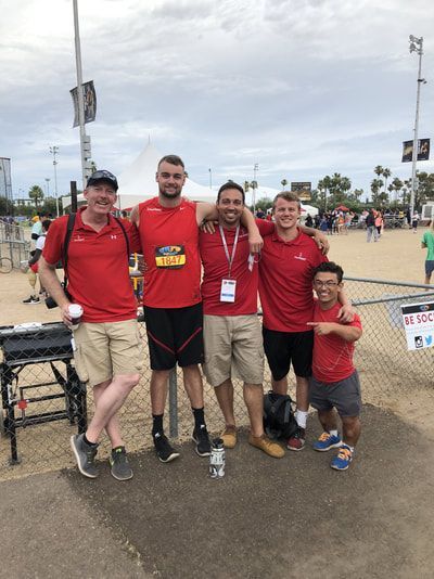 Five team members in red shirts pose arm in arm at the Desert Challenge