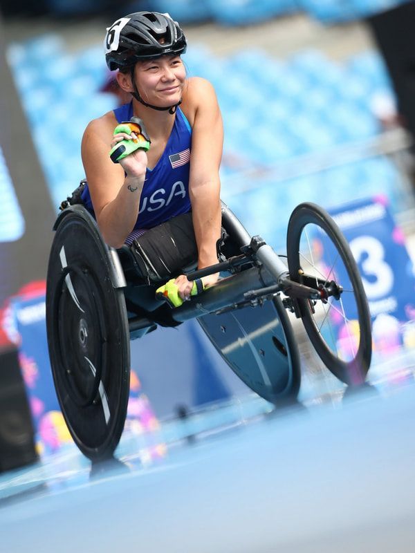 Smiling Team USA wheelchair racer in a helmet sits in her racing chair