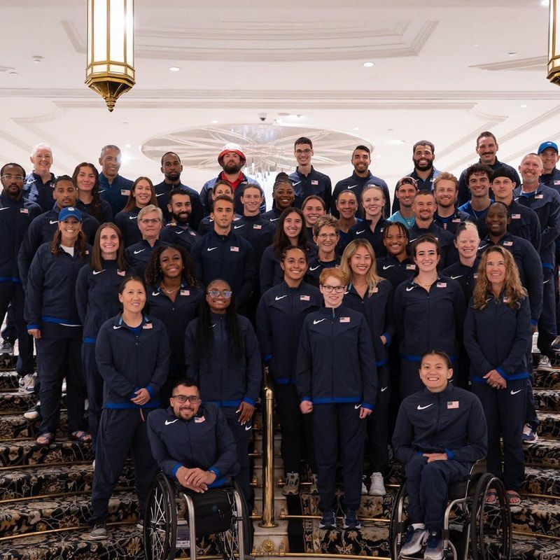 Team USA para athletics squad in navy jackets poses on a grand hotel staircase