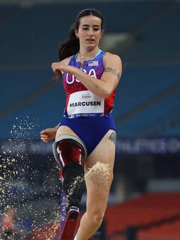 Team USA long jumper with a prosthetic leg steps out of the pit, sand flying