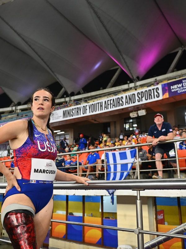 Team USA athlete with a red prosthetic leg looks up near the packed stands