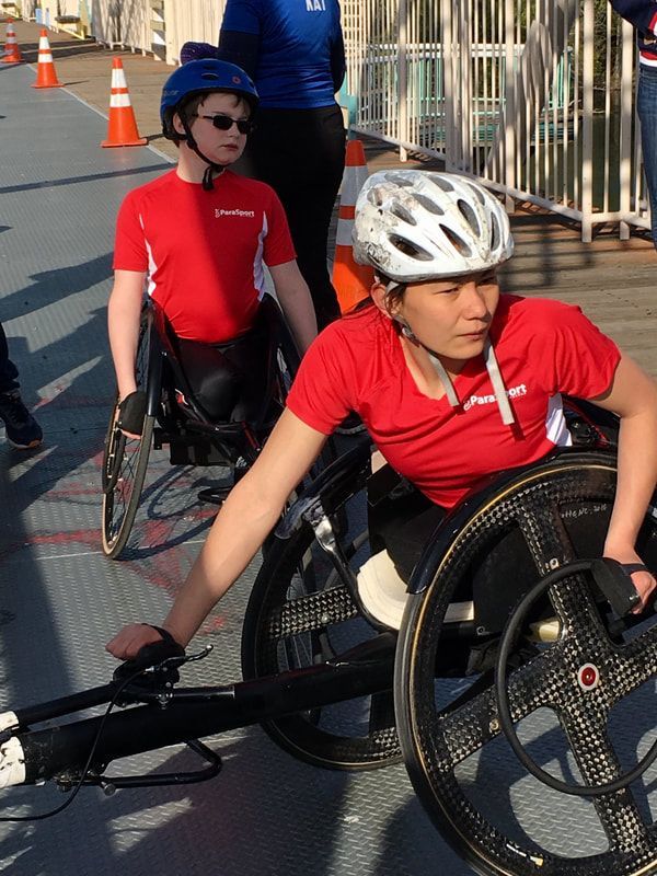 Racer in a white helmet and red ParaSport shirt sets up a racing chair