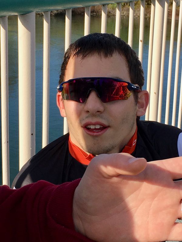 Athlete in mirrored sunglasses grins at the camera on a footbridge