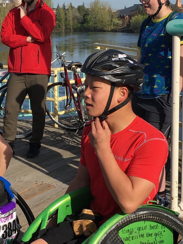 Athlete in a red shirt fastens a helmet strap in a green racing chair