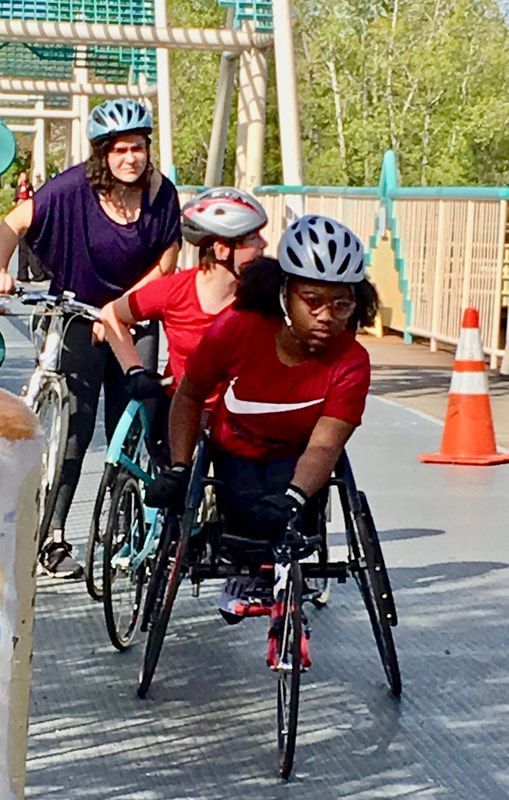 Young racer in a red shirt and white helmet rolls off a footbridge