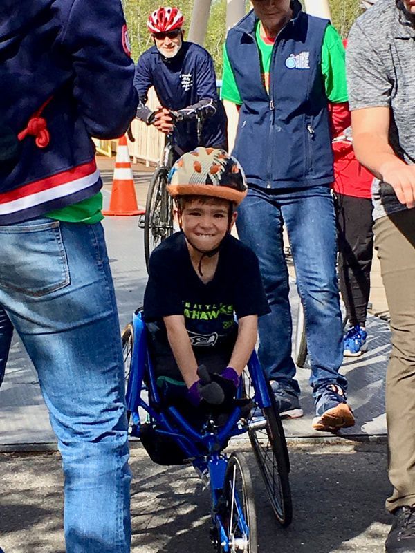 Smiling young racer in a patterned helmet waits in a blue chair among adults