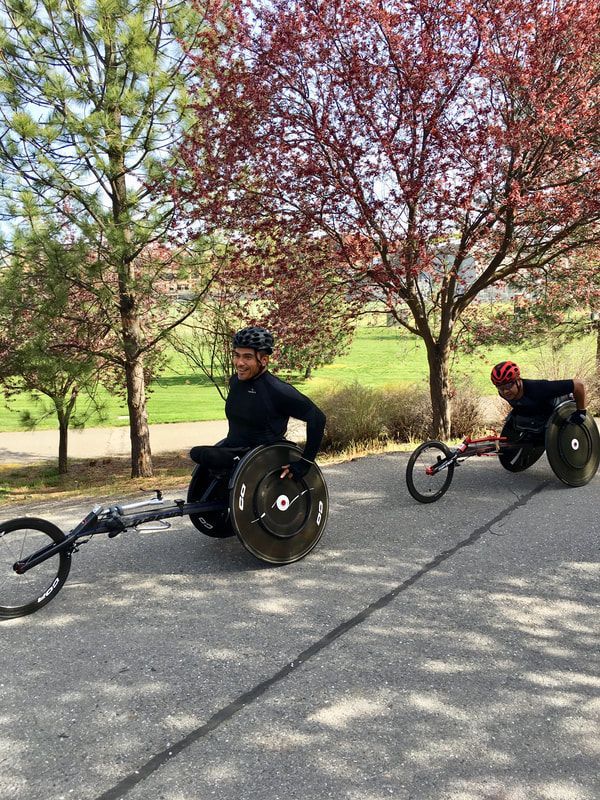 Two racers in black roll along a path under red-leafed trees