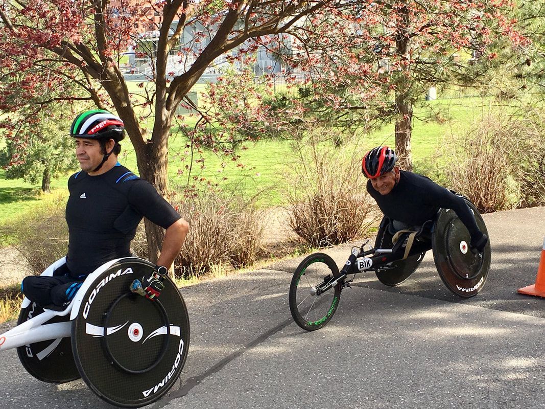 Racer in a green, white and red helmet leads another past flowering trees