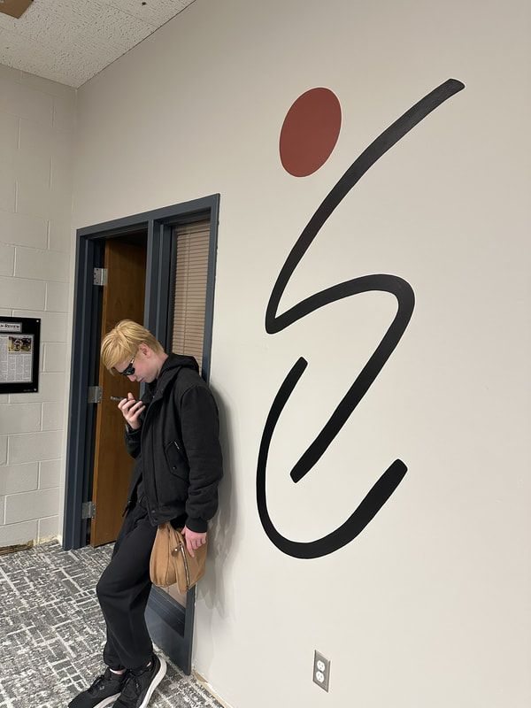 Person in sunglasses on a phone leans beside a ParaSport logo wall mural