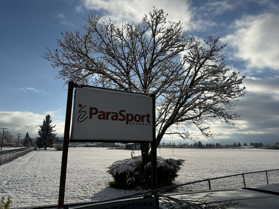 ParaSport Spokane roadside sign beside a frosted tree and snowy field