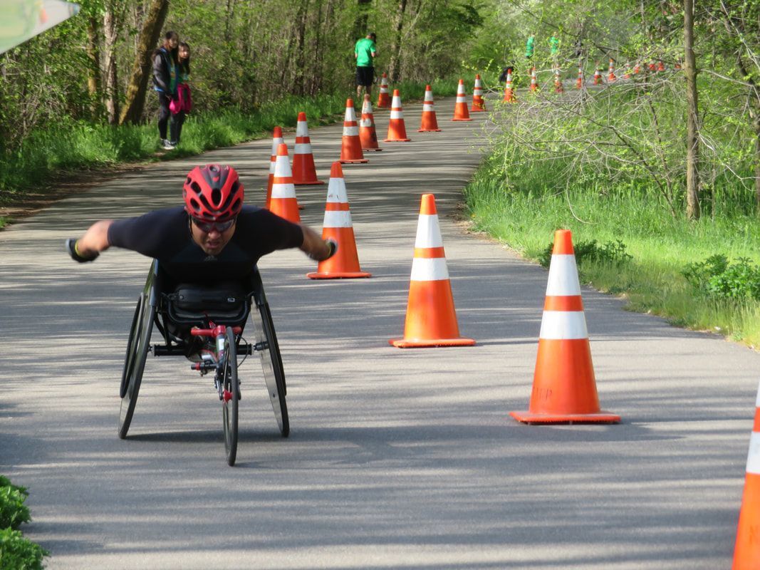 Racer in a red helmet spreads both arms wide while coasting down a coned path