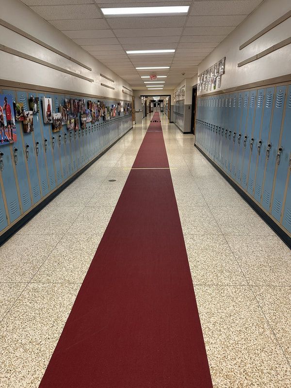 School hallway with blue lockers and a long red carpet runner