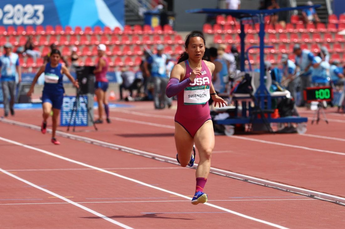 Team USA sprinter in a maroon uniform races down her lane