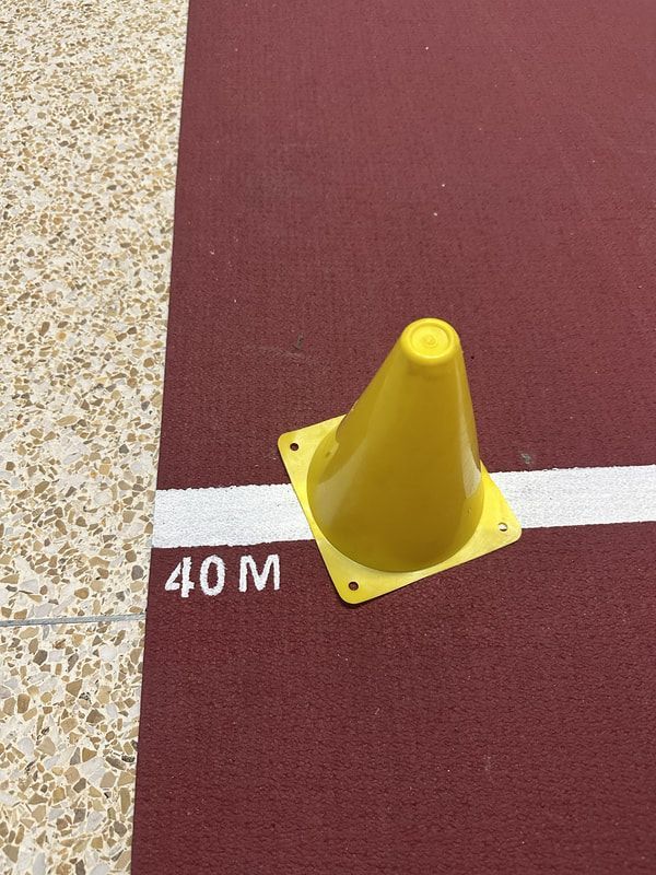 Yellow cone marks the 40 meter line on a red indoor sprint lane