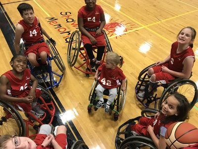 Young players in red jerseys smile up at the camera from the court