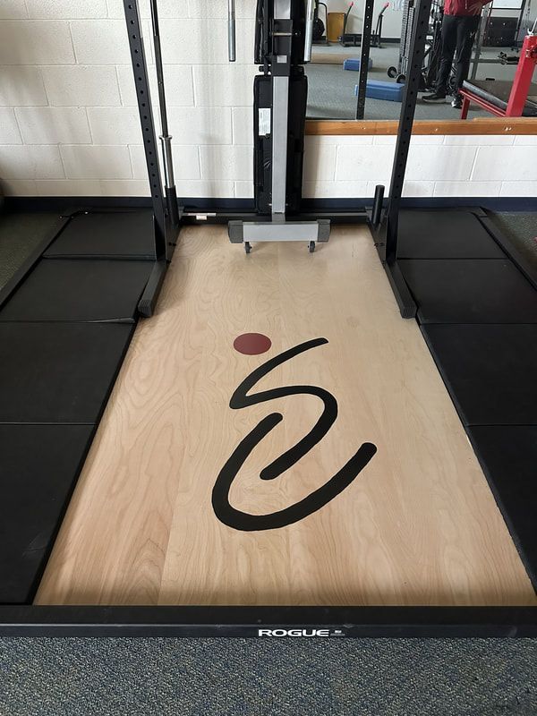 Weightlifting platform with the ParaSport logo inlaid in the wood