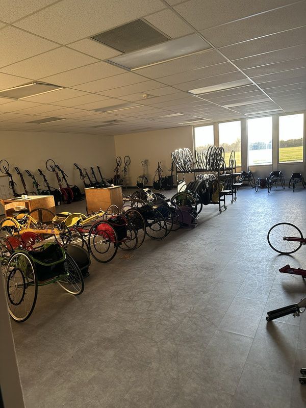 Storage room filled with racing wheelchairs and handcycles