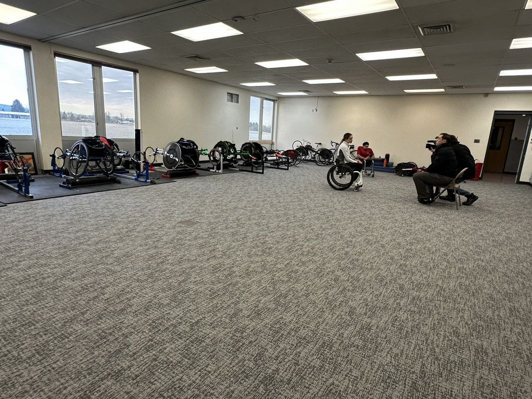 Film crew interviews an athlete in a wheelchair in the training room