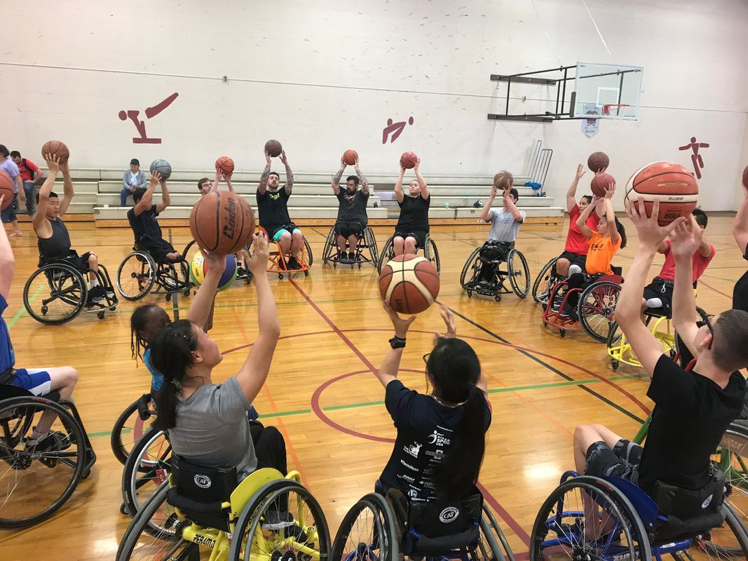 Wheelchair basketball players raise balls overhead during a shooting drill