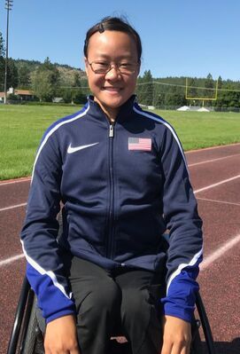 Elizabeth Floch in glasses and a Team USA jacket smiles on the track