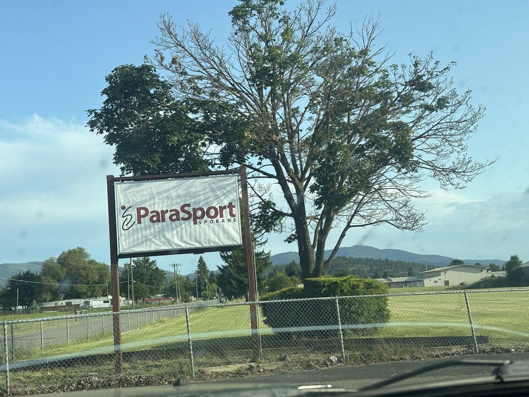 ParaSport Spokane roadside sign under a large tree on a sunny day
