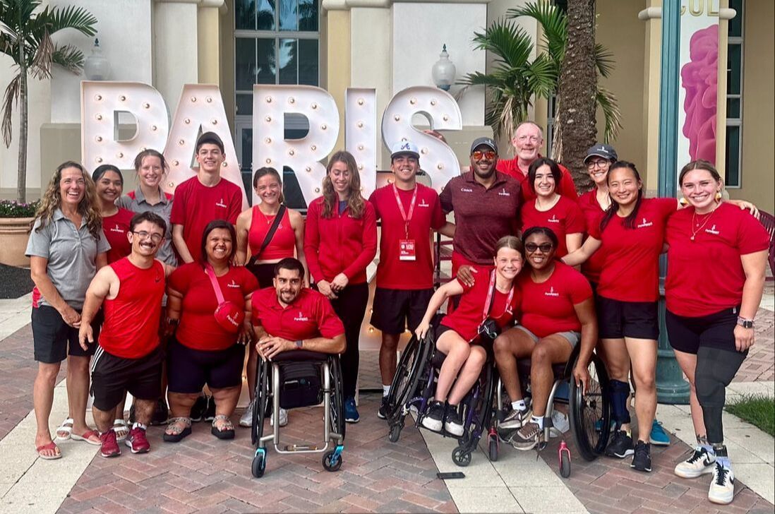 ParaSport Spokane athletes and staff in red pose by PARIS letters at the trials