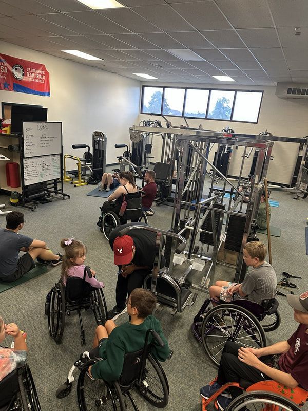 Young athletes in wheelchairs use gym machines in the training room