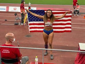 Para track athlete holds a US flag behind her on the track after competing