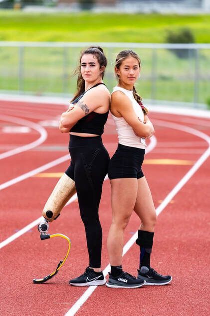 Athletes Lindi Marcusen and Annie Carey standing back to back on a track