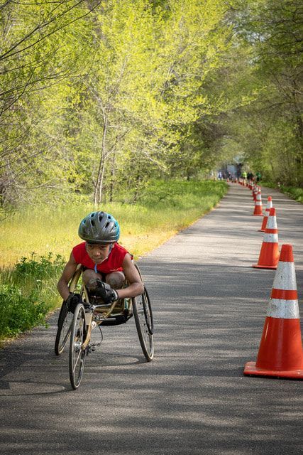 Young racer in a red shirt rolls down a leafy trail lined with orange cones