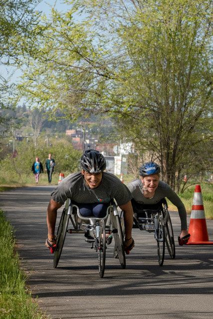 Two racers in gray shirts push side by side toward the camera