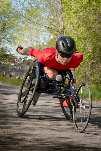 Racer in a red shirt and black helmet swings one arm back mid-push