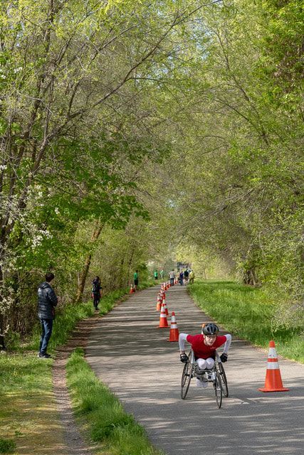 Racer in a red shirt rolls down a leafy trail as people watch from the side