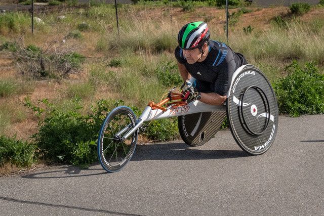 Racer in a green, white and red helmet glides in a white racing chair by brush