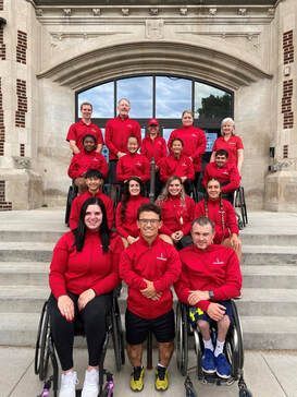 2021 Paralympic Trials team in red jackets poses on stone steps