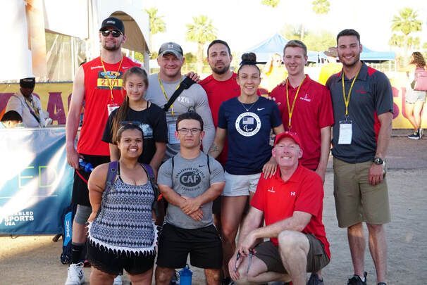 Athletes and coaches pose under palm trees at a Disabled Sports USA event