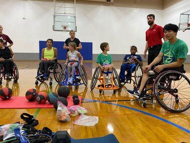 Young athletes in wheelchairs gather with coaches around medicine balls