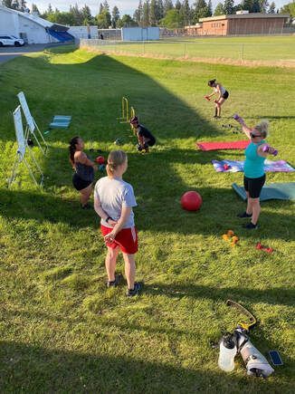 Athletes rotate through an outdoor fitness circuit on a grassy field