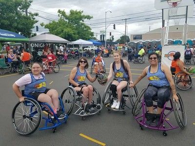 Sassy Rollettes team in matching blue tanks pose in wheelchairs at Hoopfest