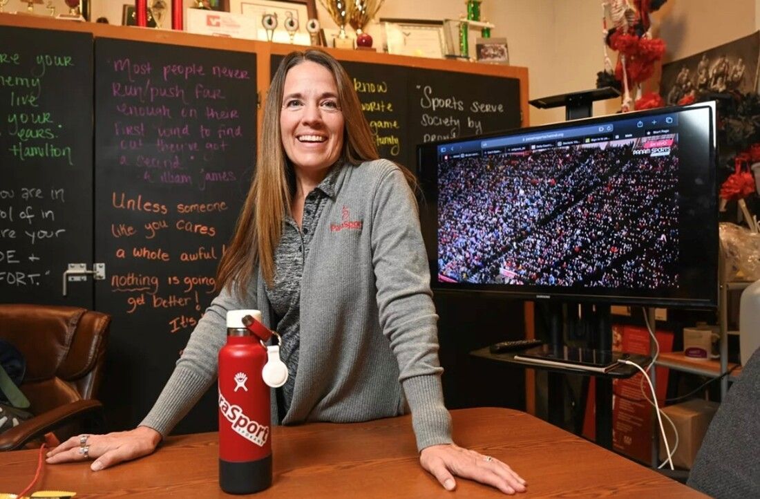 Teresa Skinner smiles at a desk beside a ParaSport water bottle
