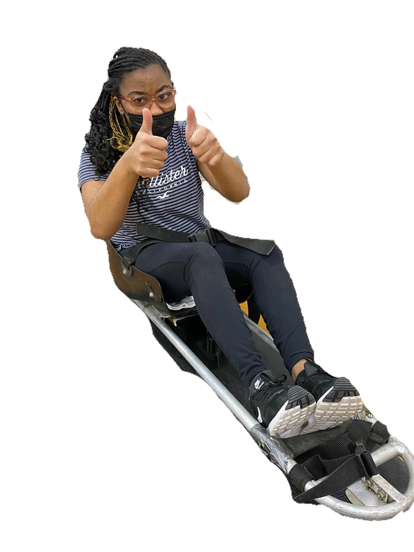 Sled hockey player in a face mask gives two thumbs up from her sled