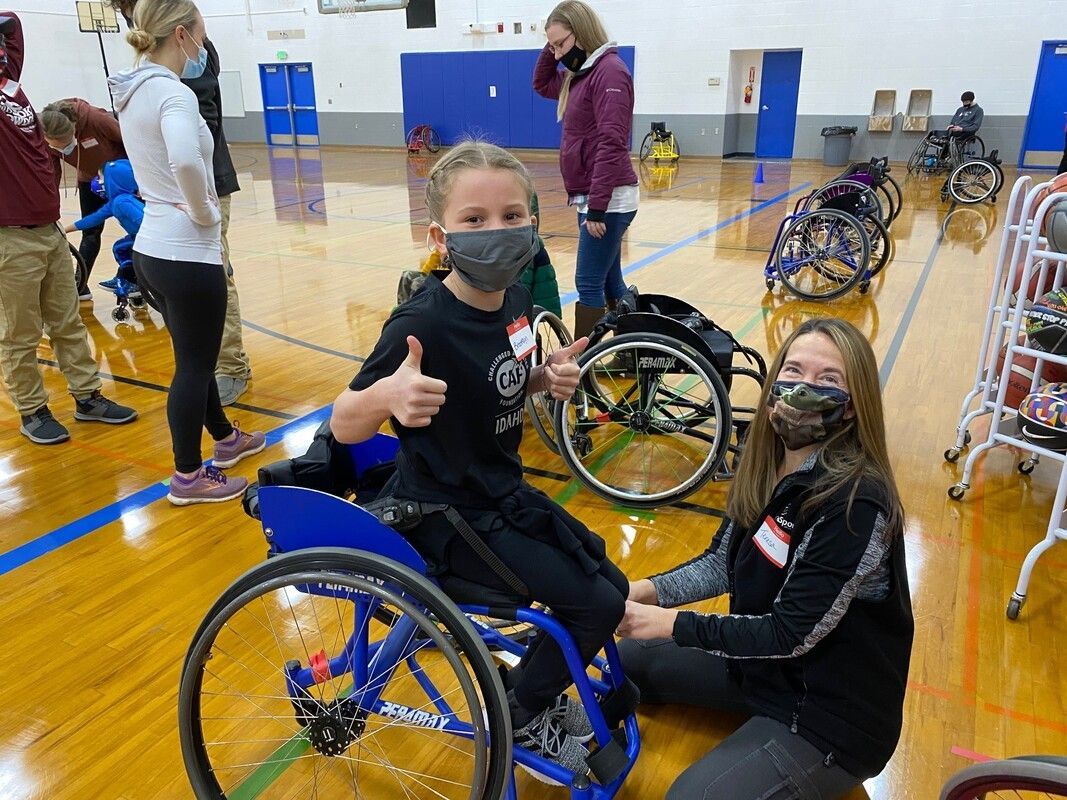 Masked young player gives a thumbs up from a sport wheelchair in a gym