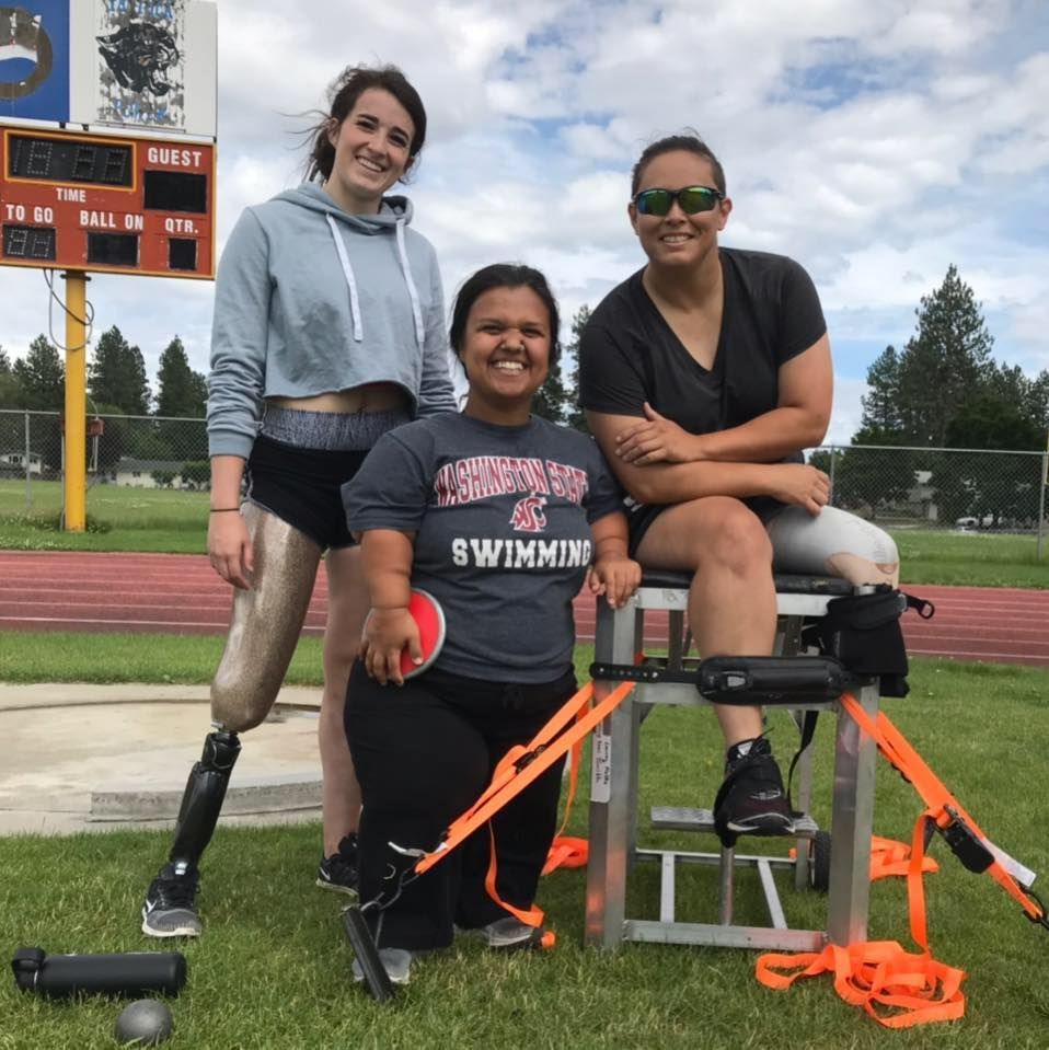 Three throwers pose by a seated throwing frame, one holds a discus