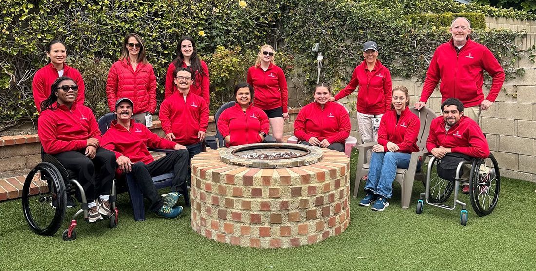 ParaSport Spokane team in red jackets poses around a fire pit at 2024 nationals