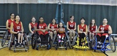 Wheelchair basketball team in red jerseys lines up in front of a dark curtain
