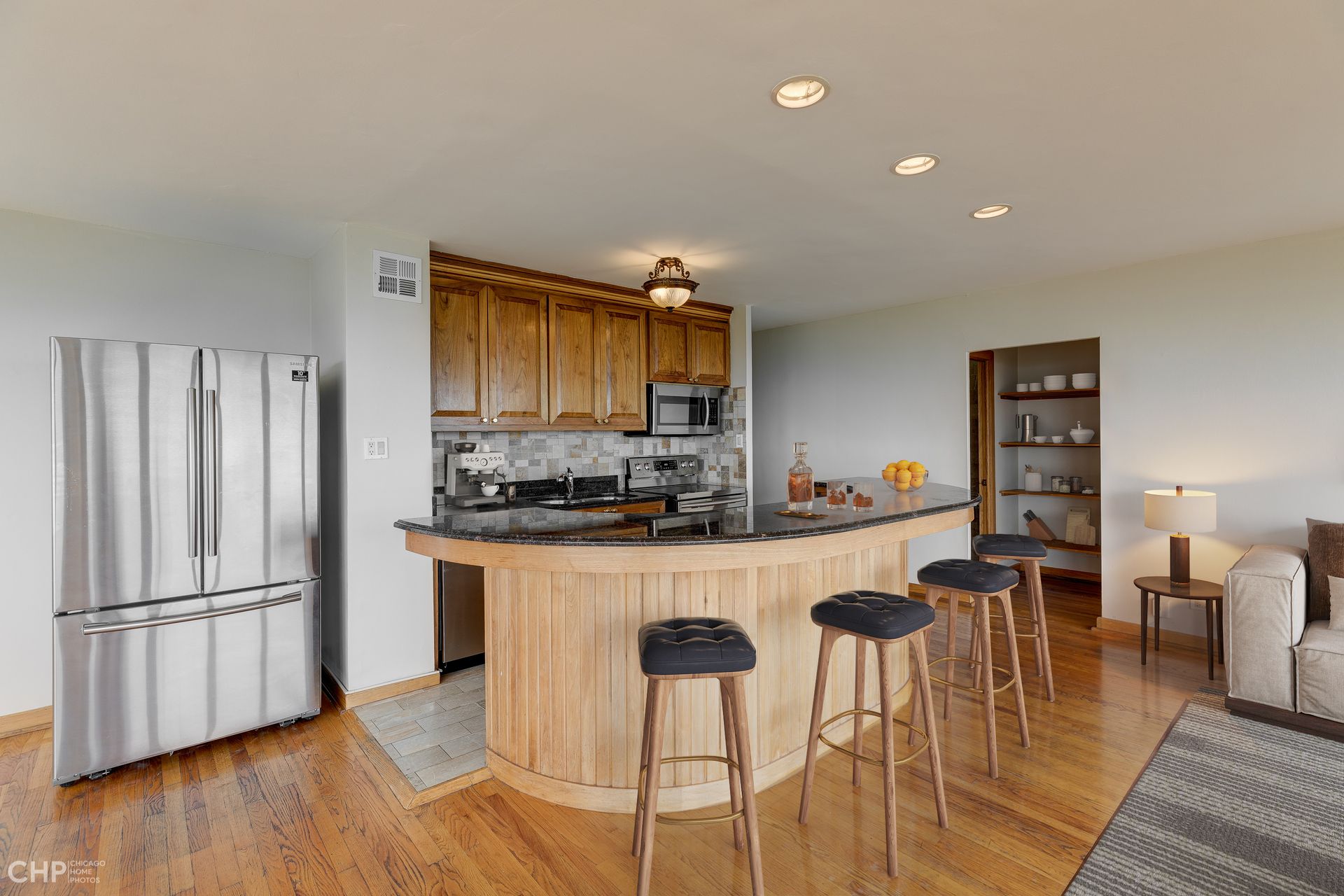 A kitchen with a bar and stools and a refrigerator