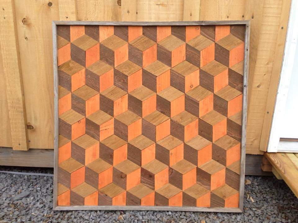 Abstract orange and brown geometric wooden panel leaning against a wooden wall outdoors