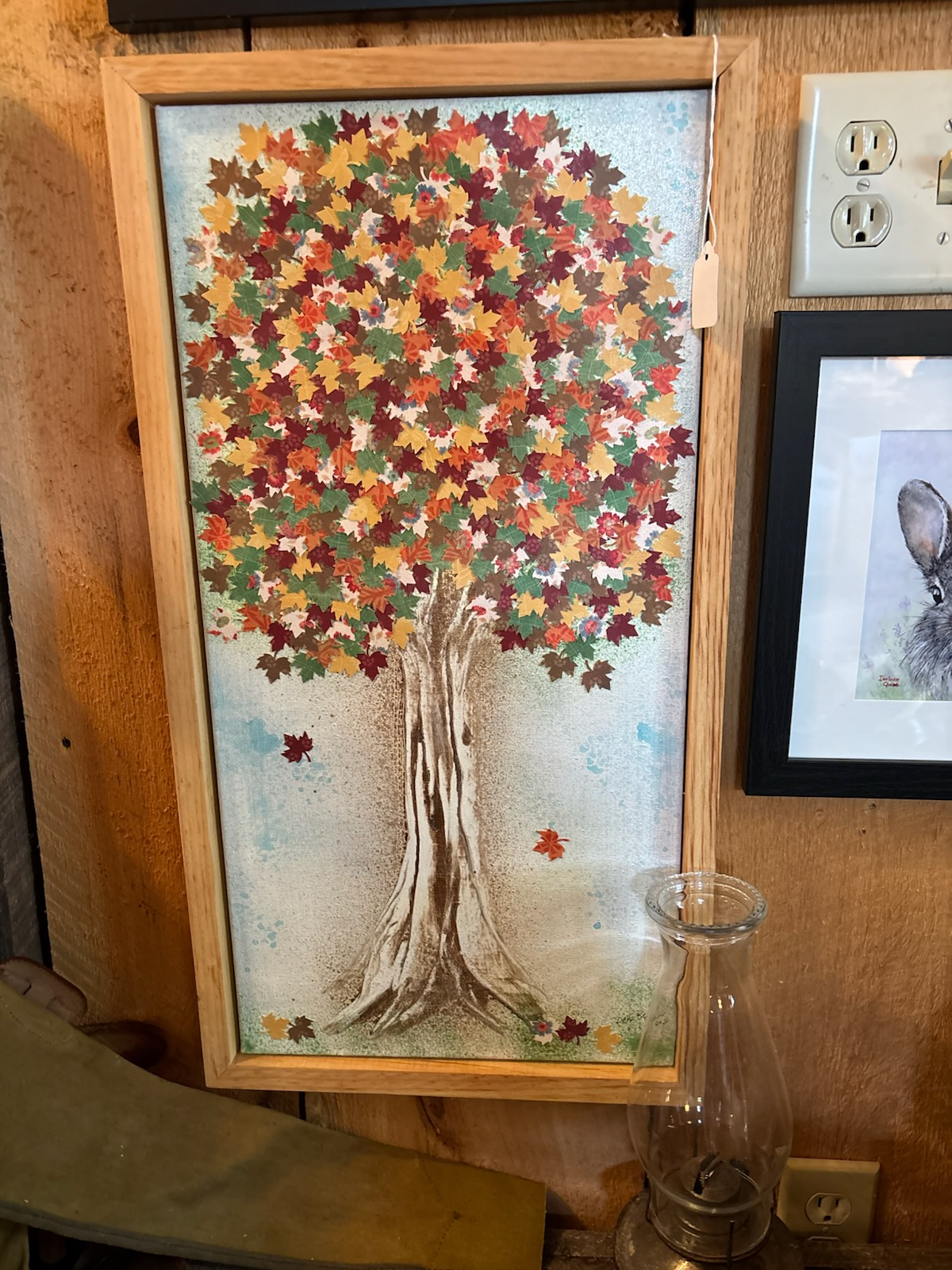 Framed painting of a tree with multicolored leaves on a wall. Paintings by Dena Martin